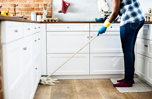 Cleaner dusting ceiling fan blades using extended duster in high-ceiling room